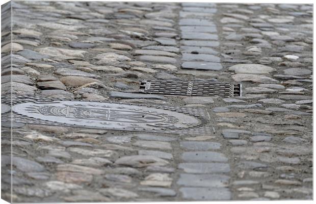 Paving of river rock and manhole covers cast iron Canvas Print by Adrian Bud