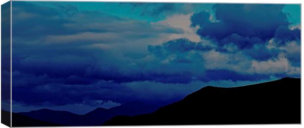 Silhouette Mountains with a stormy blue sky in Ice Canvas Print by Sue Bottomley