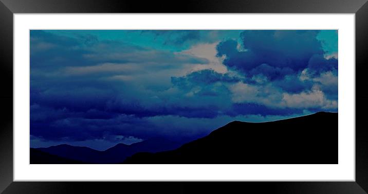 Silhouette Mountains with a stormy blue sky in Ice Framed Mounted Print by Sue Bottomley