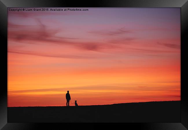 Female walking her dog, silhouetted at sunset. Wal Framed Print by Liam Grant