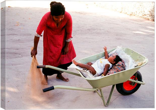  Mother keeps child in a wheel burrow while cleani Canvas Print by Hassan Najmy