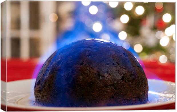 Christmas Pudding on a table, with a Christmas tre Canvas Print by Dave Carroll