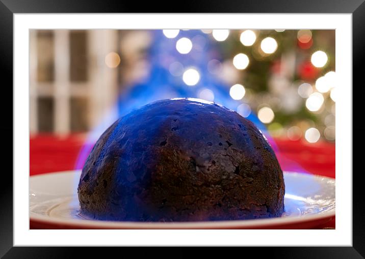Christmas Pudding on a table, with a Christmas tre Framed Mounted Print by Dave Carroll