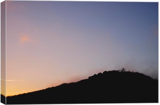 Male silhouetted on mountain top at sunset. Derbys Canvas Print by Liam Grant