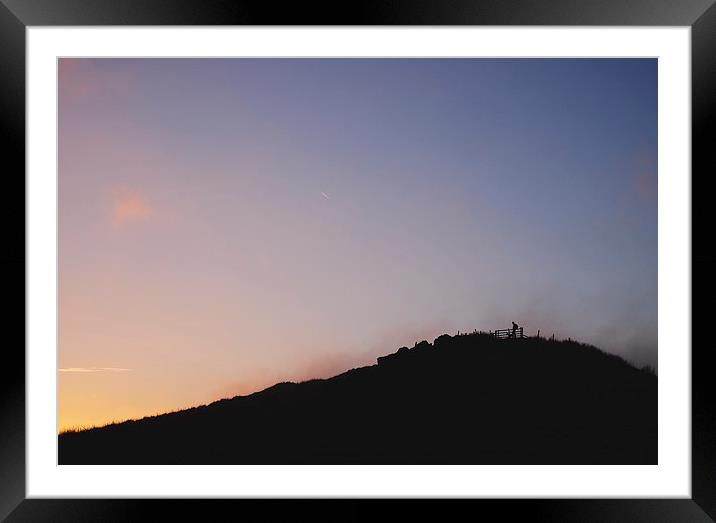 Male silhouetted on mountain top at sunset. Derbys Framed Mounted Print by Liam Grant