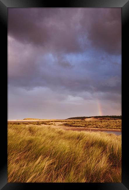 Storm clouds and rainbow at sunset. Holkham, Norfo Framed Print by Liam Grant