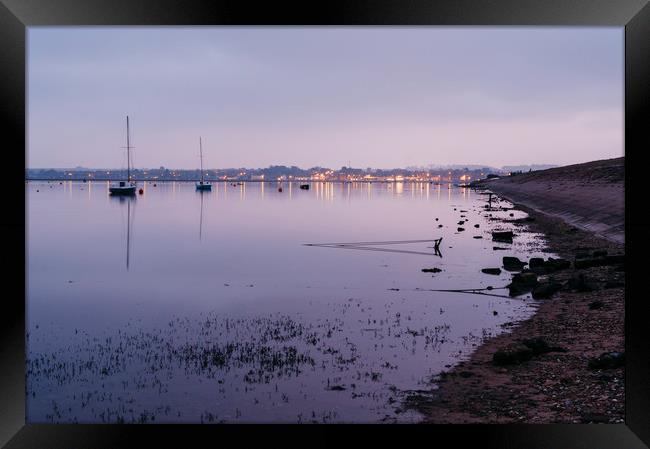 Boats and distant harbour reflected at twilight. W Framed Print by Liam Grant