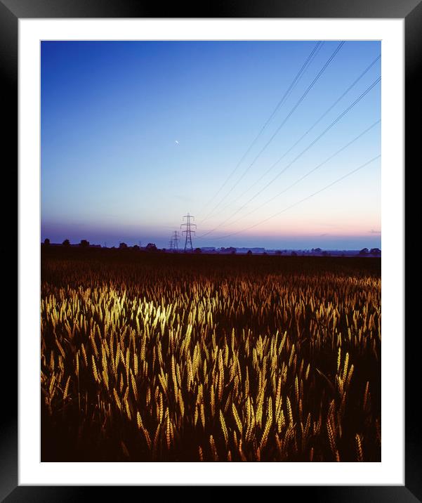 Wheat field and electricity pylon lit by torch lig Framed Mounted Print by Liam Grant