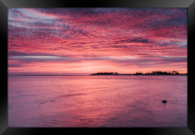 Pink dawn sky reflected in the surface of the sea. Framed Print by Liam Grant