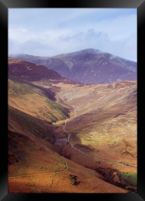 Distant tracks leading up a mountainside in Autumn Framed Print by Liam Grant