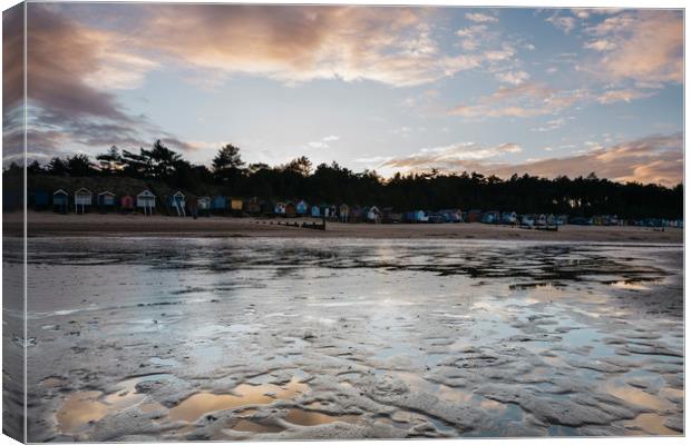 Sunset sky and beach huts reflected in a water at  Canvas Print by Liam Grant