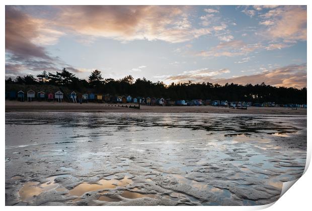 Sunset sky and beach huts reflected in a water at  Print by Liam Grant