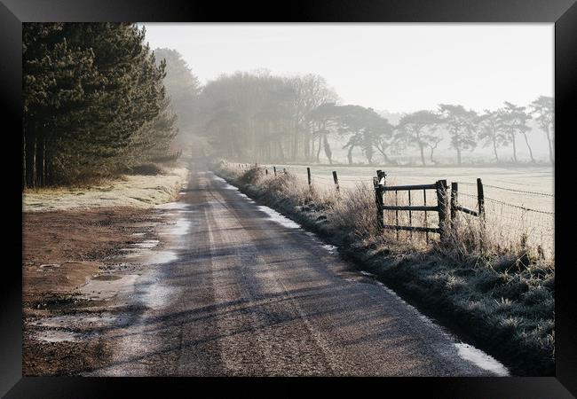 Remote frozen country road at sunrise. Norfolk, UK Framed Print by Liam Grant