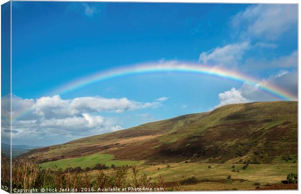 Rainbow over blue sky in the Brecon Beacons Canvas Print by Nick Jenkins