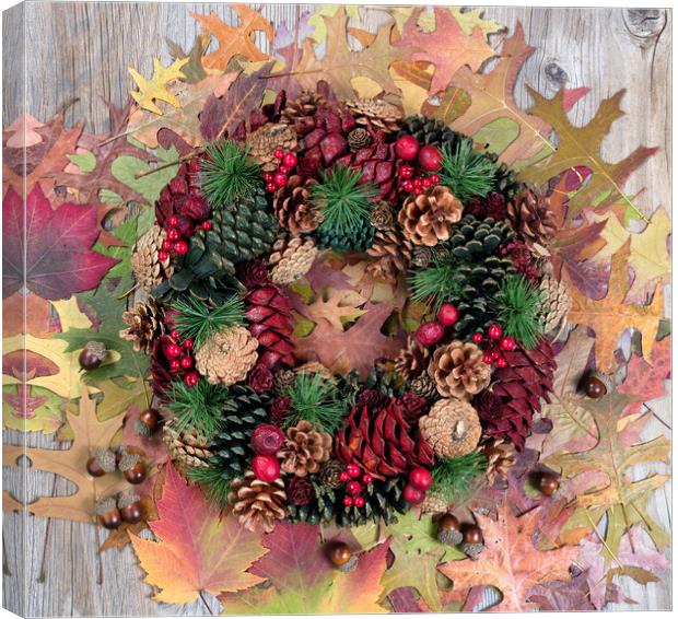 Autumn cone wreath and leaves on rustic wooden boa Canvas Print by Thomas Baker