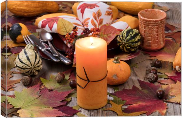 Holiday candle glowing for dinner setting for fall Canvas Print by Thomas Baker