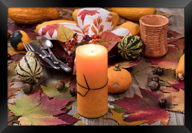 Holiday candle glowing for dinner setting for fall Framed Print by Thomas Baker