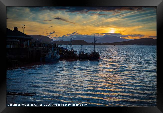 The sun sets on Oban harbour and fishing boats Framed Print by George Cairns