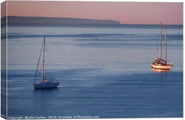 Pink Sky Sunrise flooding over boats on a calm blu Canvas Print by john hartley