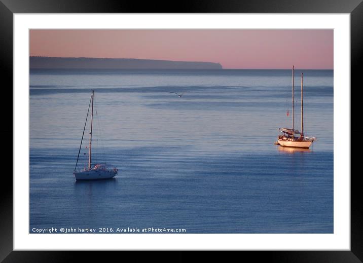 Pink Sky Sunrise flooding over boats on a calm blu Framed Mounted Print by john hartley