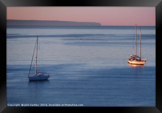 Pink Sky Sunrise flooding over boats on a calm blu Framed Print by john hartley