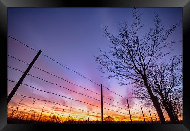 Fiery sunset viewed through barbed fence Framed Print by Simon Bratt LRPS