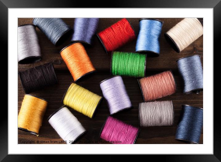 Colorful cotton reels scattered on dark wood Framed Mounted Print by Simon Bratt LRPS