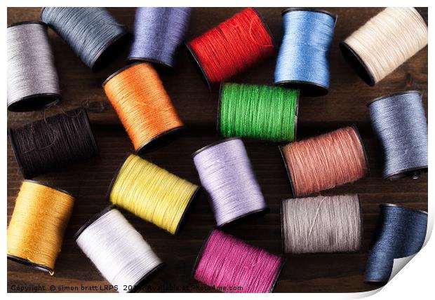 Colorful cotton reels scattered on dark wood Print by Simon Bratt LRPS