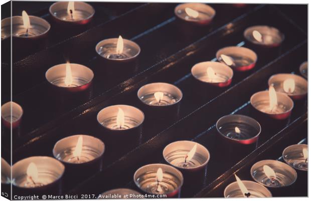 Rows of brightly burning votive candles Canvas Print by Marco Bicci