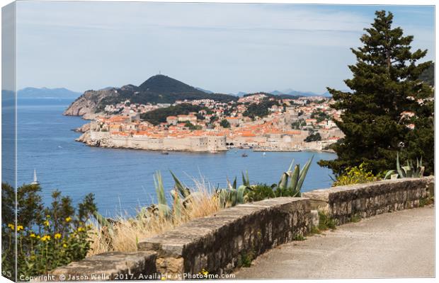 Dubrovnik's old town seen over a curving coastal r Canvas Print by Jason Wells