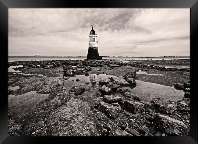 Lighthouse on a rocky shore Framed Print by David McCulloch