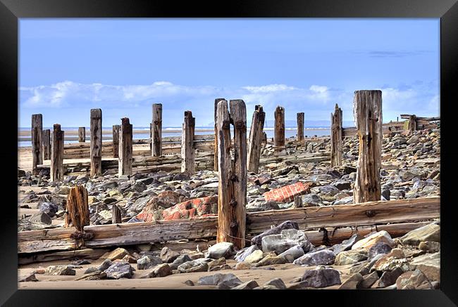 Battered Remains of Groynes along the beach Framed Print by Mike Gorton