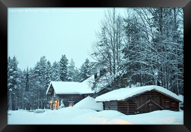 Log cabins nestled in the snow laden trees at dusk Framed Print by Teresa Cooper