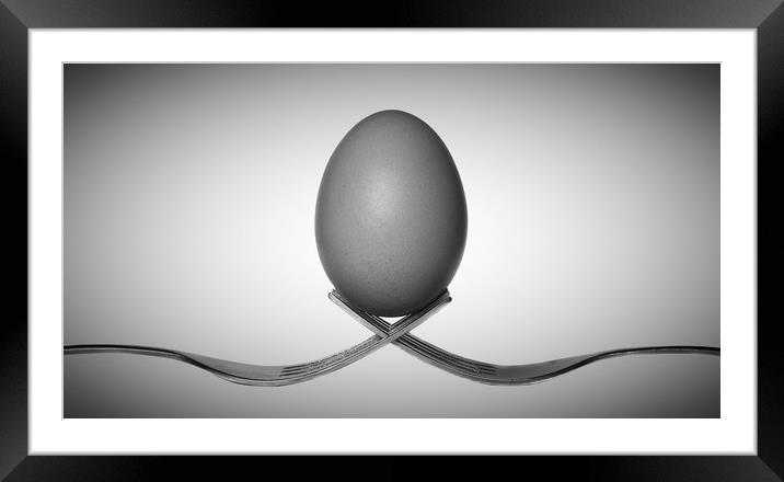 Egg balancing on two forks Framed Mounted Print by Donnie Canning