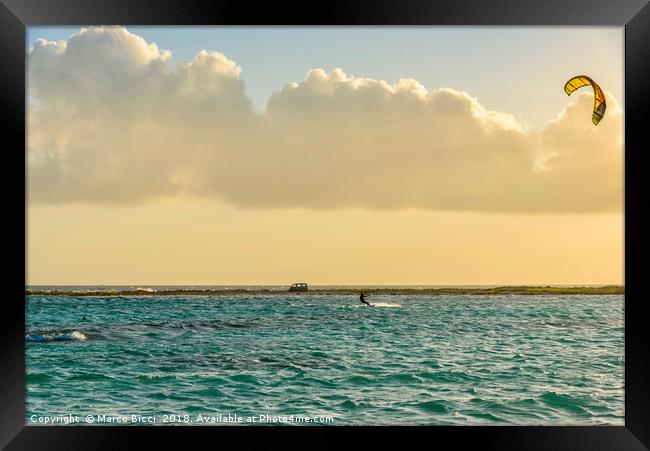 A man practices kitesurfing at sunset Framed Print by Marco Bicci