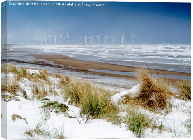 Cold conditions on a deserted beach with snowy cli Canvas Print by Peter Jordan