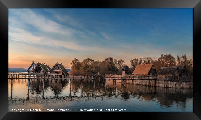 Huts and bridge over water at sunset Framed Print by Daniela Simona Temneanu