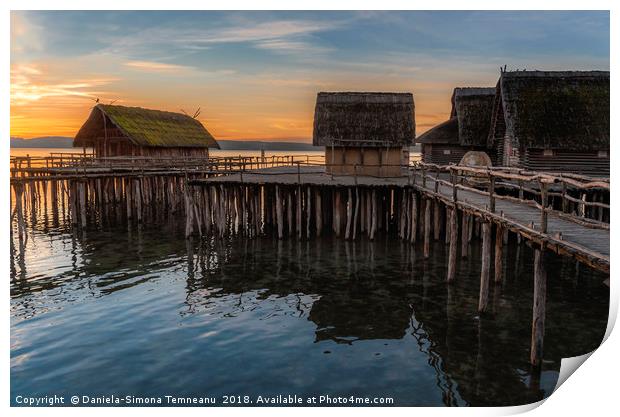 Old wooden cabins over water at sunset Print by Daniela Simona Temneanu
