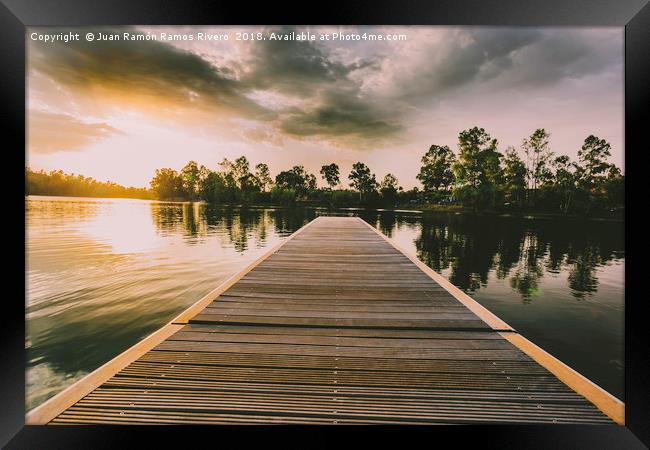 Wooden jetty over the lake at sunset in a sky with Framed Print by Juan Ramón Ramos Rivero
