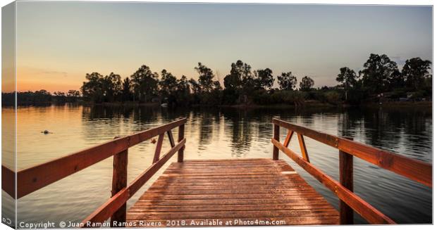 Reddish wooden pier over the lake with calm waters Canvas Print by Juan Ramón Ramos Rivero