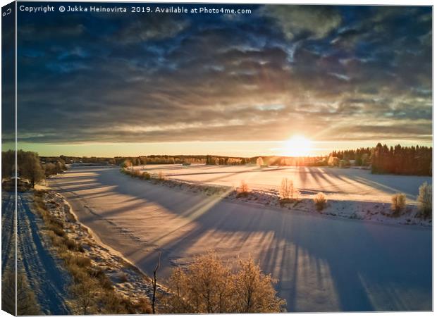 Sun Rising Over The Frozen River Canvas Print by Jukka Heinovirta