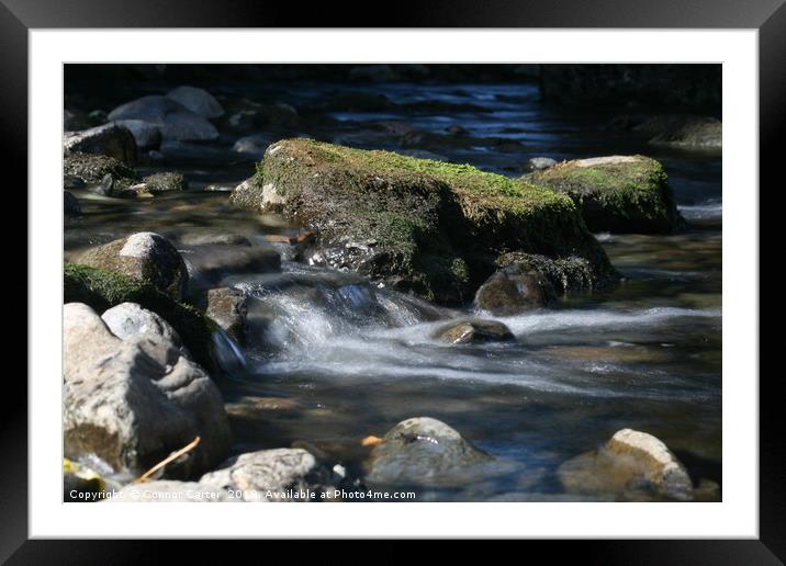 Water flowing over a rock Framed Mounted Print by Connor Carter