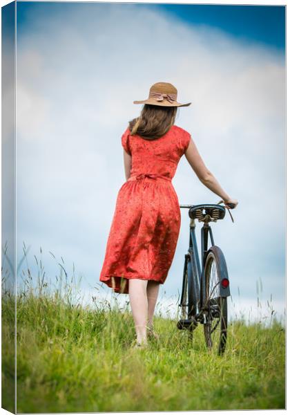 Women pushing vintage bicycle in a field. Canvas Print by Maggie McCall