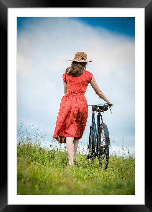Women pushing vintage bicycle in a field. Framed Mounted Print by Maggie McCall