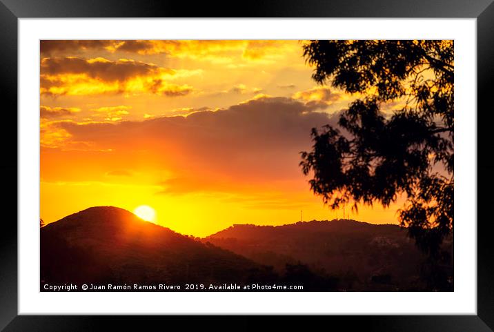 Sunset sun behind the mountain with orange sky Framed Mounted Print by Juan Ramón Ramos Rivero