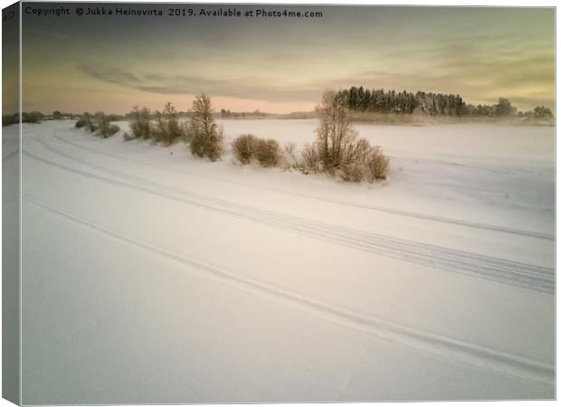 Snow Mobile Tracks On An Icy River Canvas Print by Jukka Heinovirta