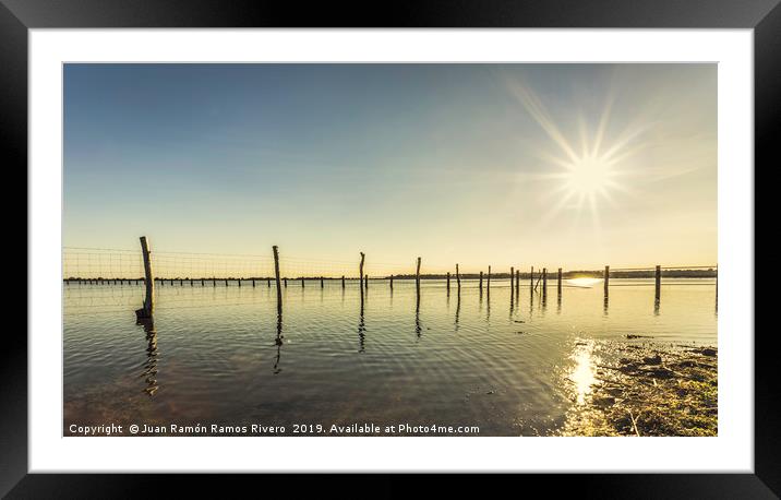 Wooden post and wire fence on a lake Framed Mounted Print by Juan Ramón Ramos Rivero
