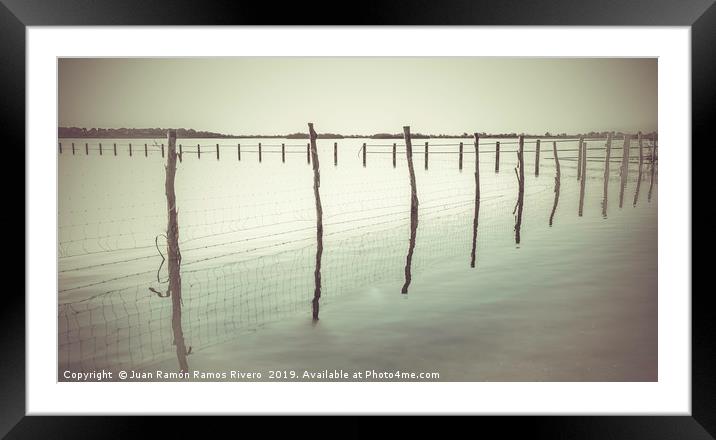 Wooden post and wire fence on a lake in black and  Framed Mounted Print by Juan Ramón Ramos Rivero