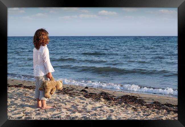 little girl with teddy bear standing on beach and  Framed Print by goce risteski
