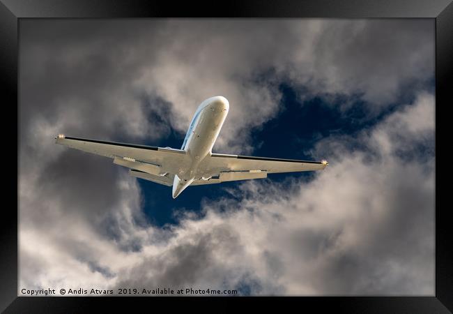 Airplane flying through a hole in storm clouds Framed Print by Andis Atvars